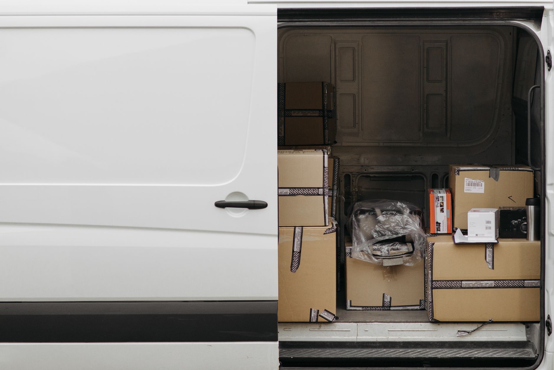 Open schuifdeur van een witte bestelbus vol dozen